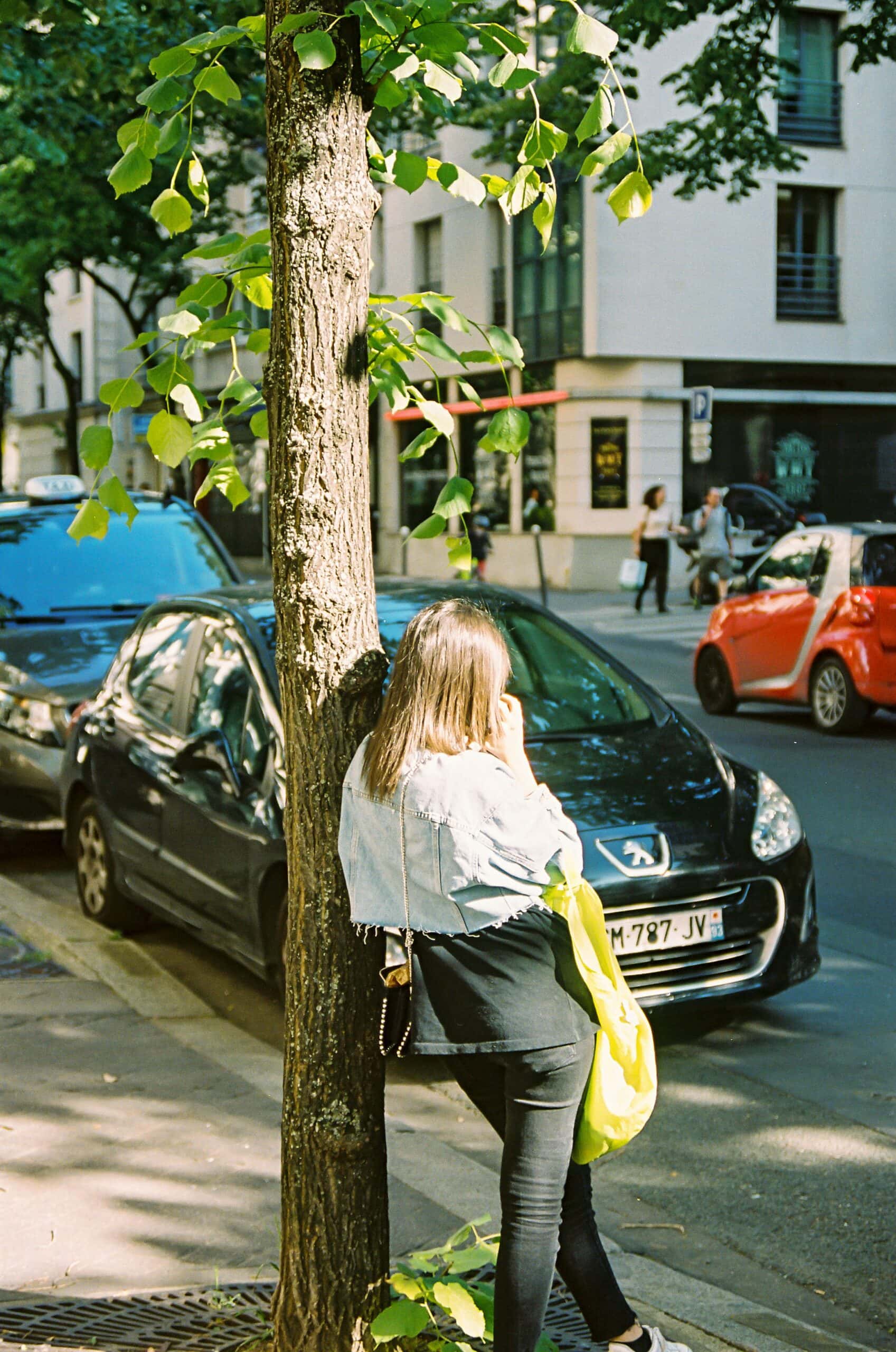 Una mujer apoyada contra un árbol.