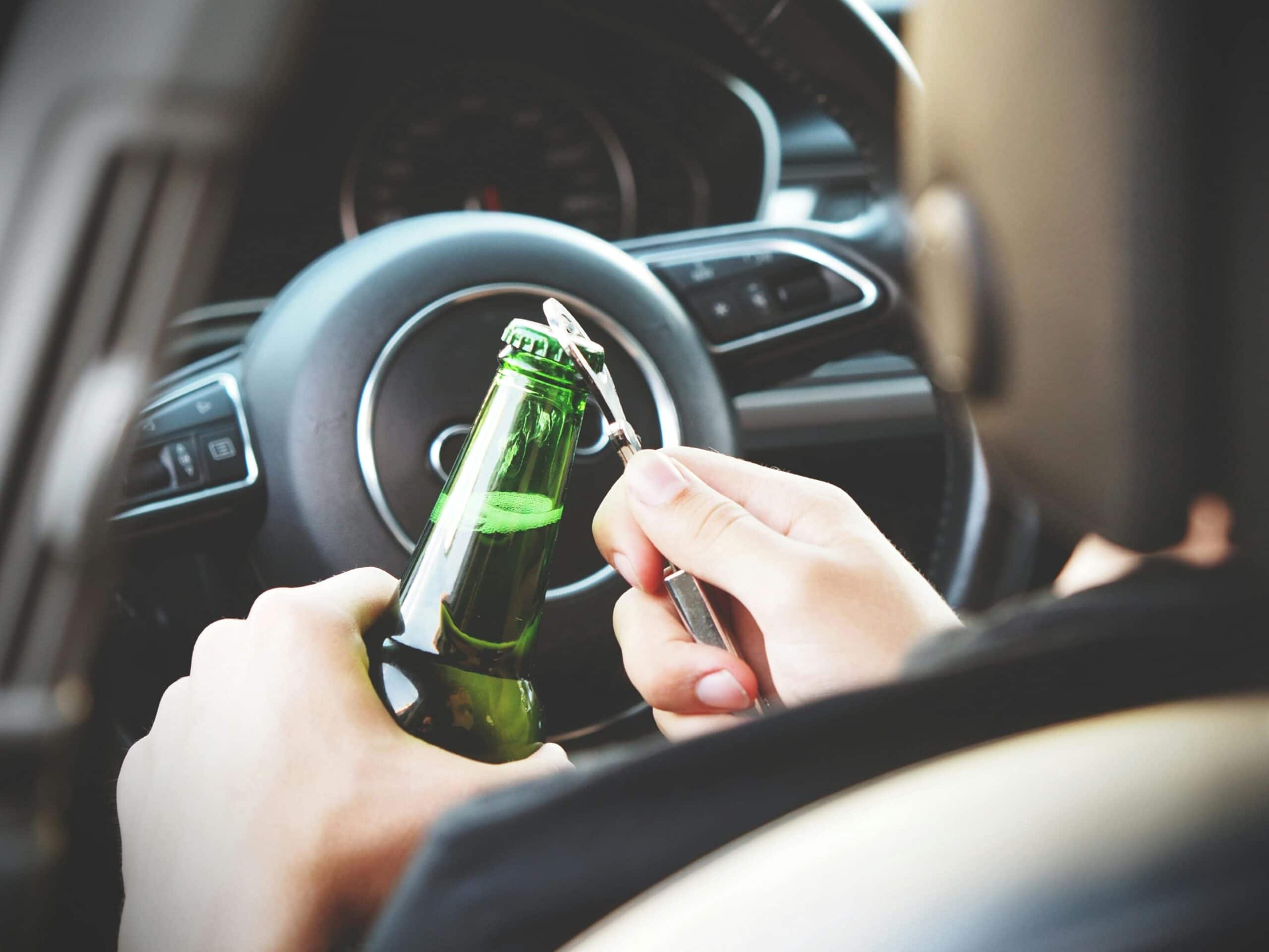 Drunk driver opening a beer by the steering.