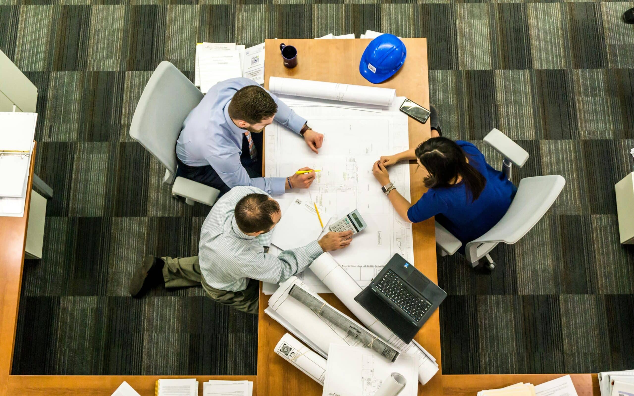 A team on a table with documents, blueprints and other devices, planning to sue a corporation.