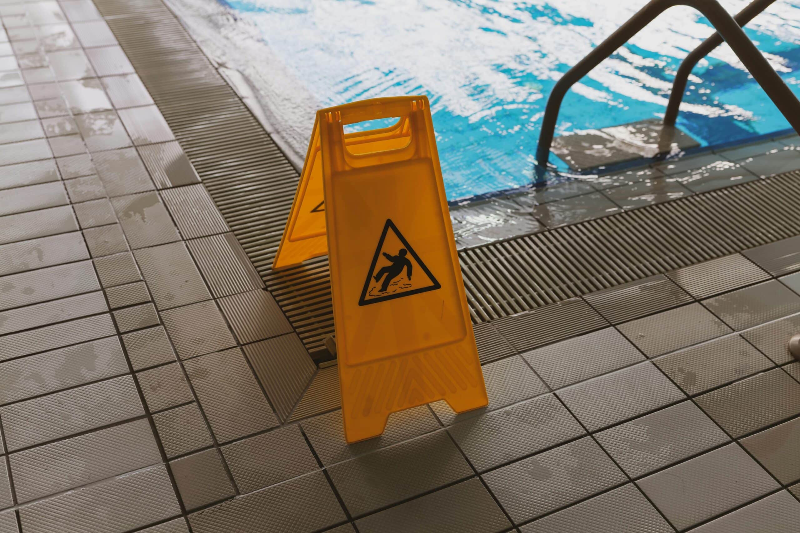 A slip and fall sign next to the pool